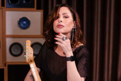 A cantora Pitty segurando uma guitarra em estúdio, diante de caixas amplificadoras