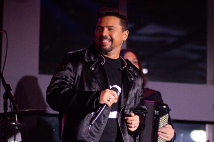 O cantor Xand Avião sorrindo com microfone na mão durante show